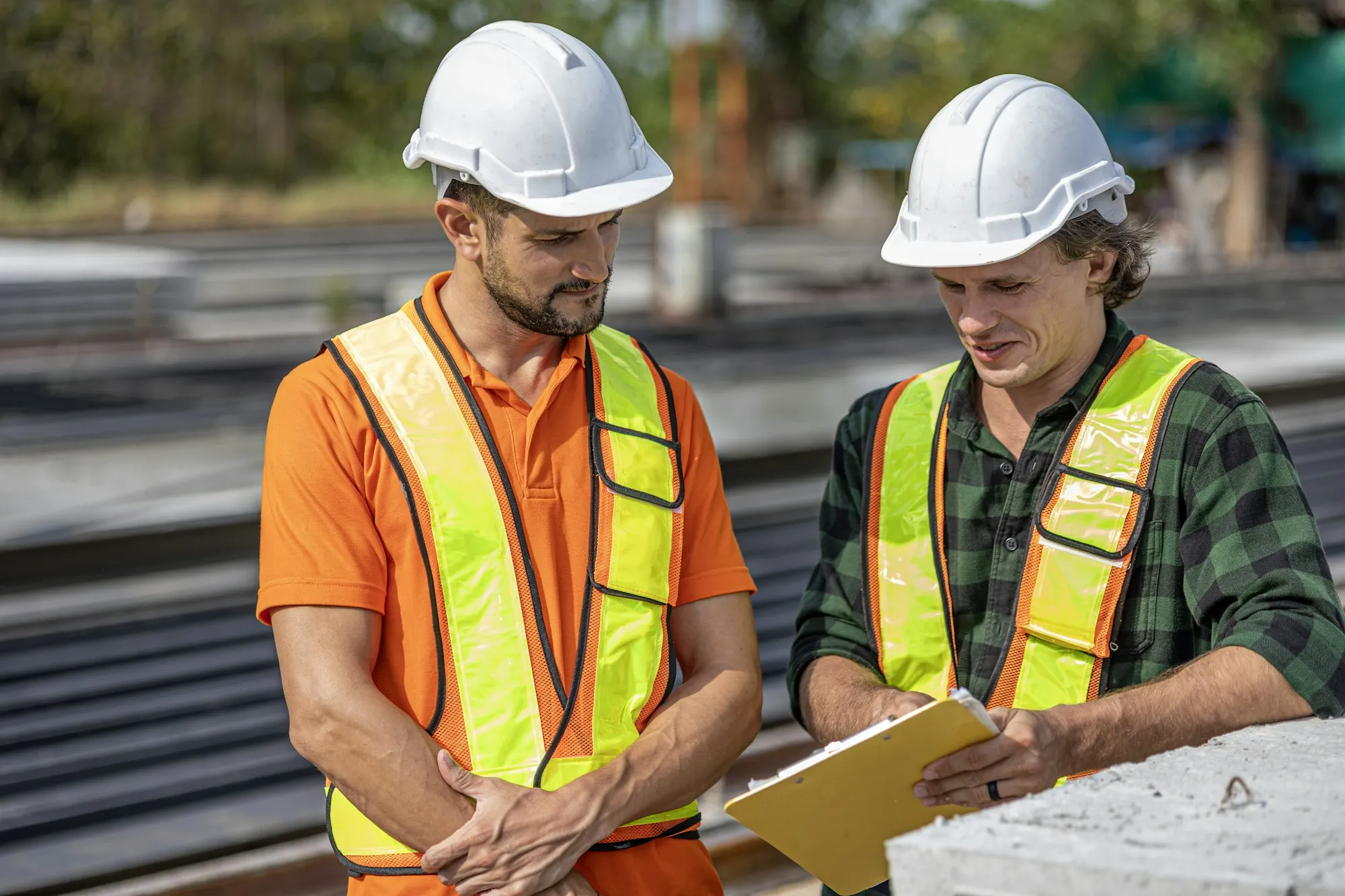 Two electricians in hard hats reviewing plans on site