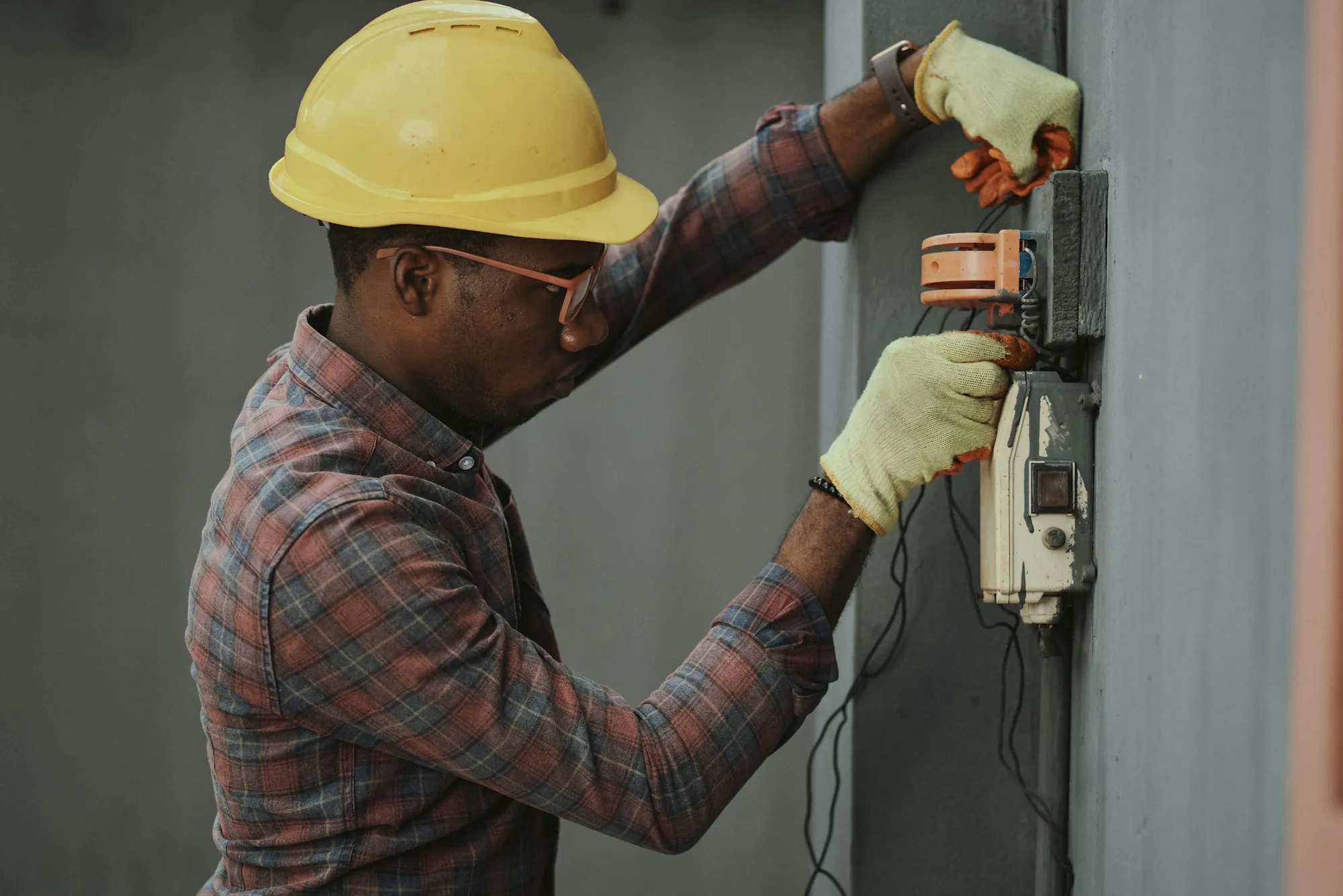 Electrician in a hard hat working on a home service panel